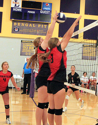 Hailey Hanson blocks a Clarkston spike as she and Sydney Shears put up a wall in a match at the Lewiston Tournament. At left is Lexi Schumacher.