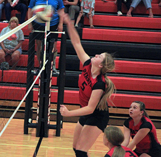 Hailey Hanson spikes the ball at Troy as Sydney Shears and Tamden Pecarovich get ready to play defense.