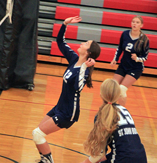 Savannah Perrin looks to put the ball over the net at C.V. as Presley Schoo, 15, and Julia Wassmuth, 2, look on.