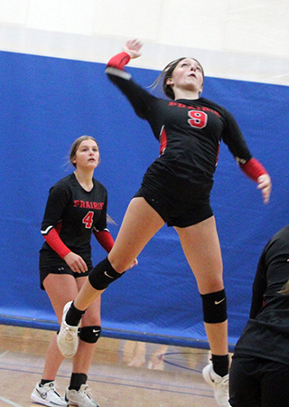 Aubree Rehder leaps to make a spike at the Genesee Tournament. Also shown is Lexi Schumacher.