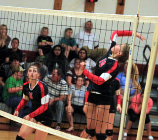 Chaye Uptmor goes up for a spike. At left is Hailey Danly.