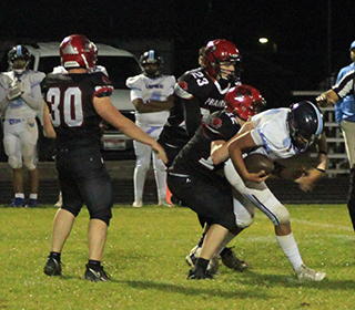 Matt Wemhoff wraps up Lapwai's quarterback for a sack to end the game. Also shown are Jake Quintal and Bennie Elven.