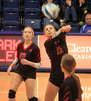 Alli Geis bumps the ball over the net. Also shown are Taylor Riener and Sydney Shears.