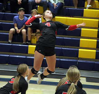 Lexi Schumacher goes up for a spike at Logos. Also shown are Sydney Shears and Hailey Hanson.